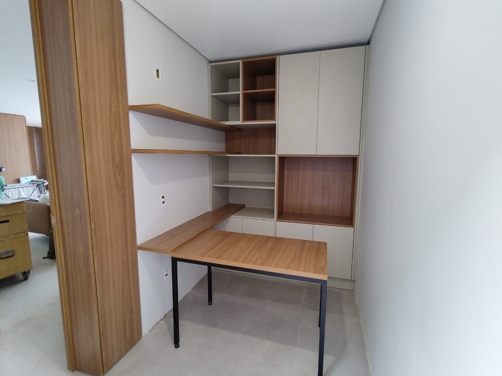 Escritório visto da porta, com mesa de pés pretos encaixada na bancada
